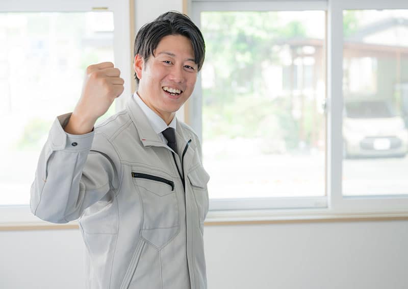 ガッツポーズをする作業服姿の男性